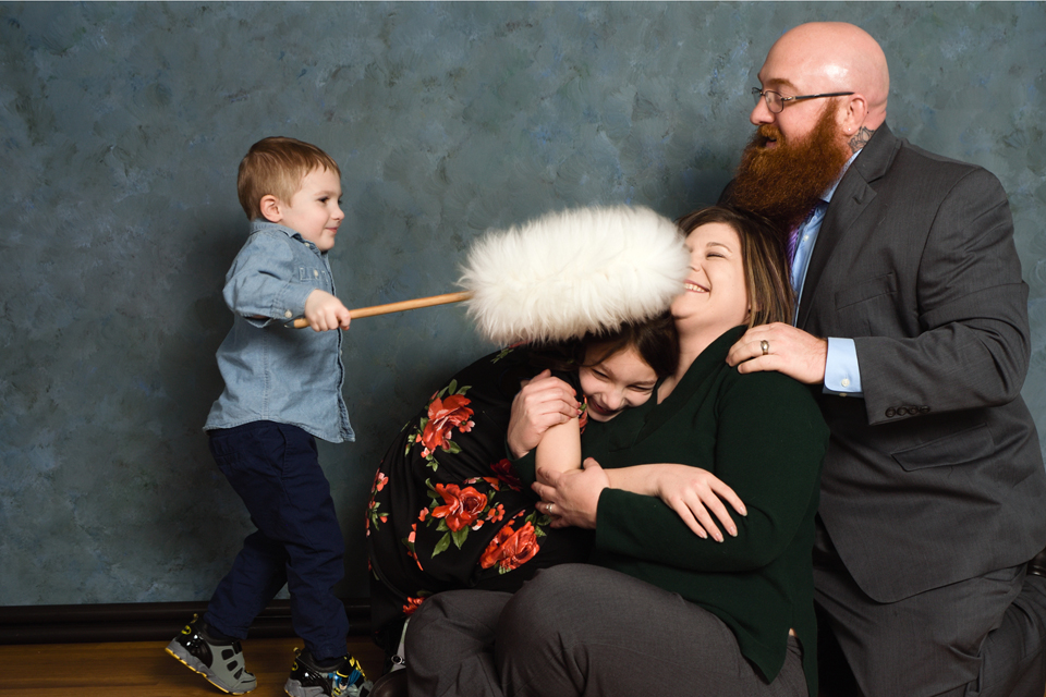 family of four with son being playful with a feather duster.
