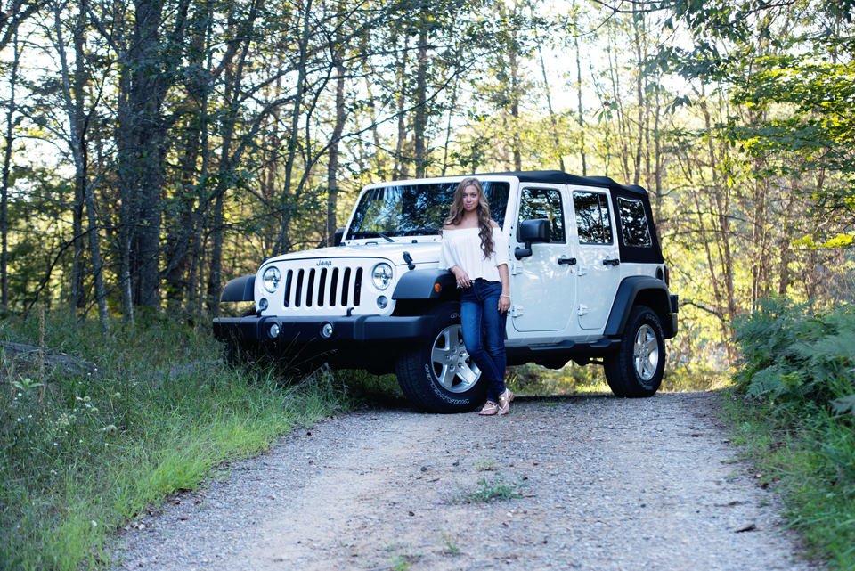 High School Senior standing in front of her Jeep.