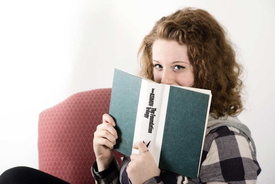 High School Senior peeking over the top of her favorite book.
