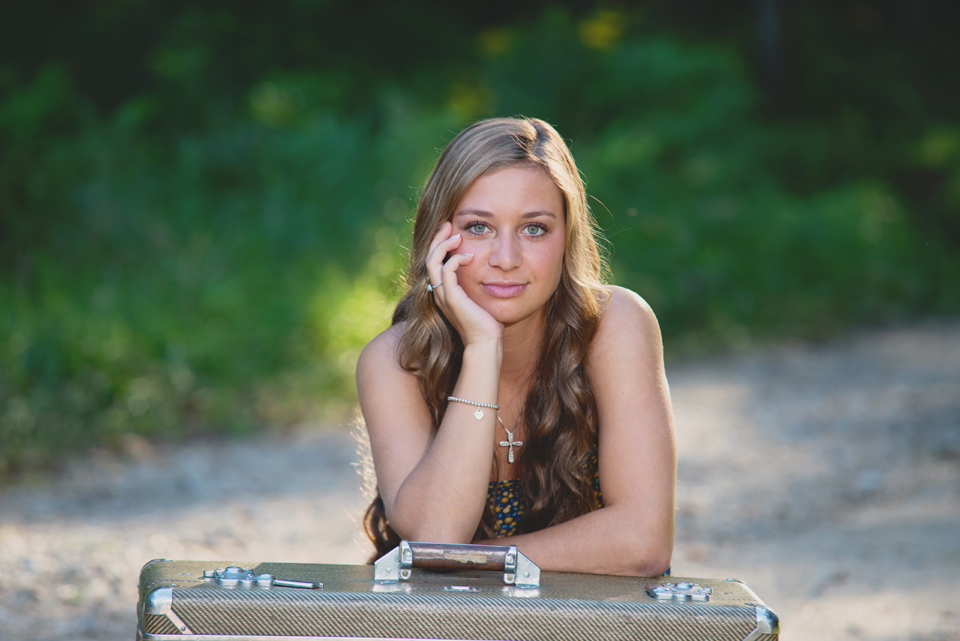 high school senior leaning on suitcase