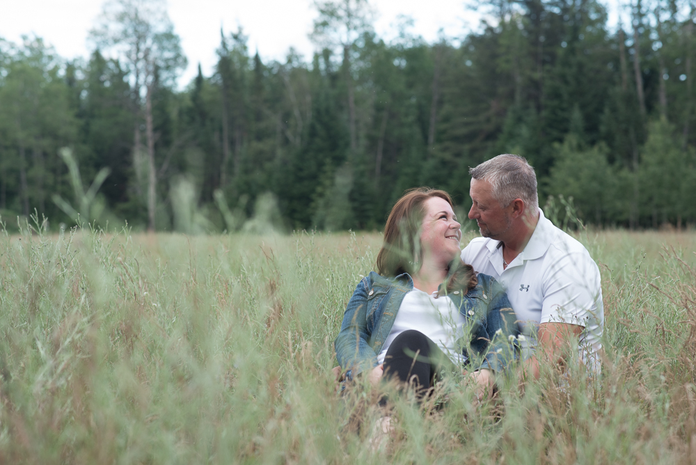 Engagement couple sitting in tall grass