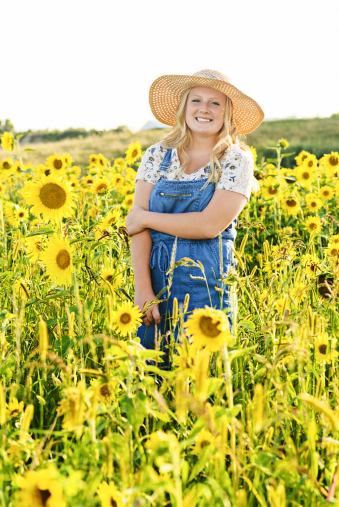High school senior girl in sunflower field with hat