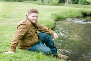 high school senior boy sitting by the houghton creek