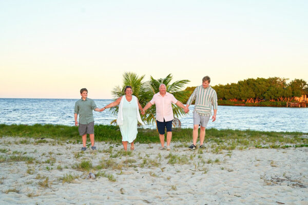 Family holding hands as they walk on the beach at sunset on beach in Belize.