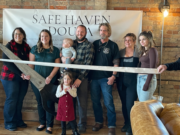Family lined up in front of the Safe Haven Doula banner, just before ribbon cutting
