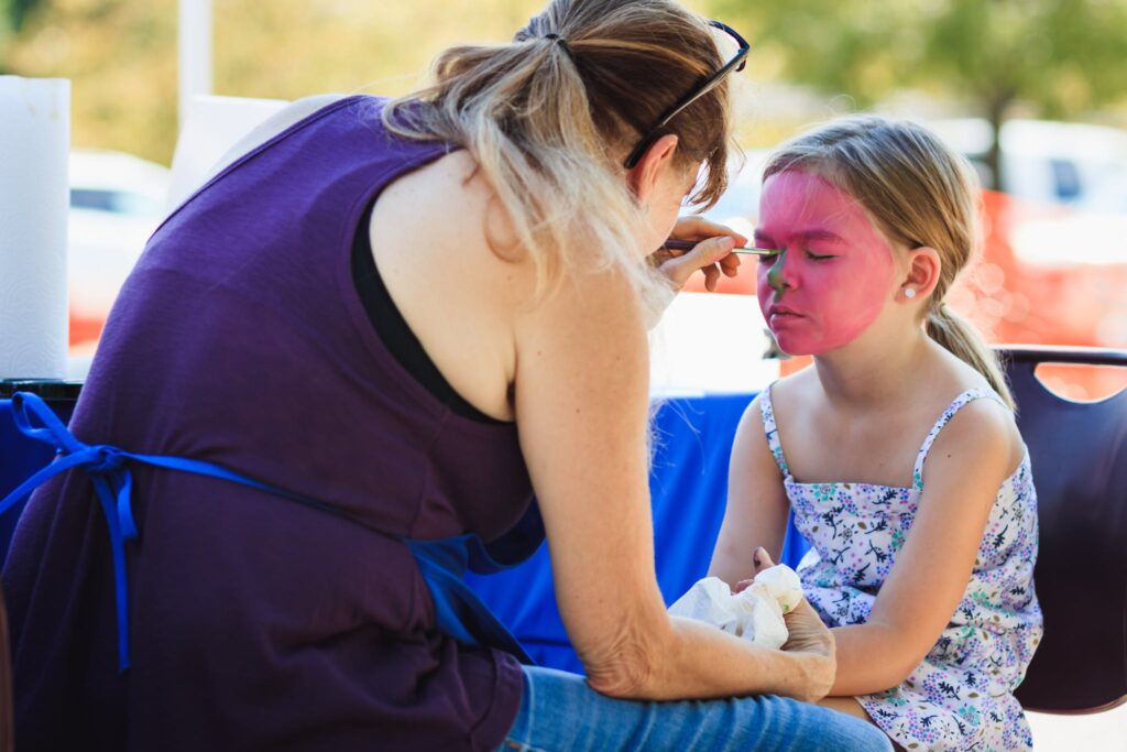 Woman Sitting On Chair painting child's face at a graduation party