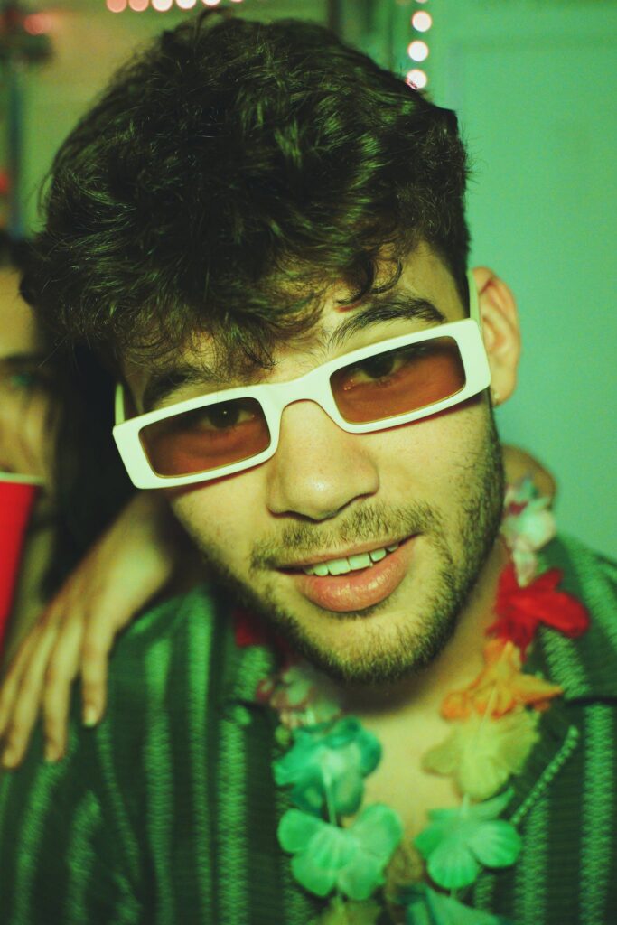 Young Man at a graduation Party Wearing Sunglasses and Hawaiian Flower Necklace