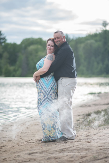Engaged Couple standing together on the beach with smoke bomb