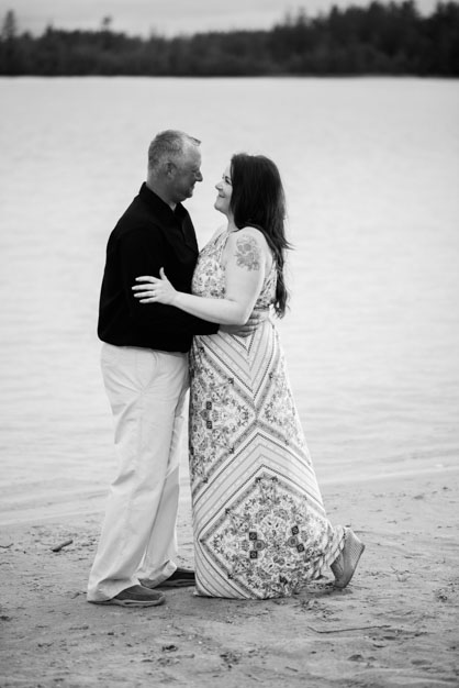 Engaged Couple standing together on the beach smiling at each other