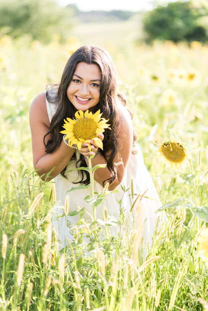 High School Senior in Sunflower field holding a large sunflower