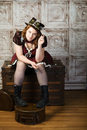 girl with steam punk outfit sitting on a trunk.