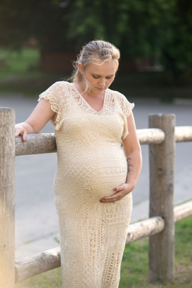 pregnant woman leaning on a fence