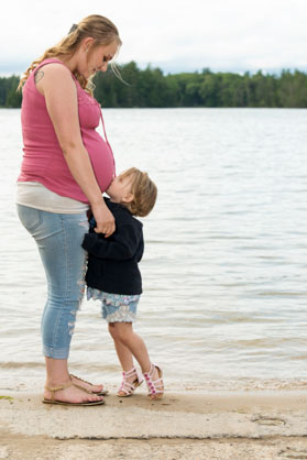 pregnant woman with little child kissing her pregnant belly.