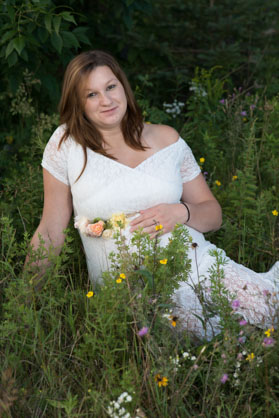 pregnant woman sitting in grass with flowers