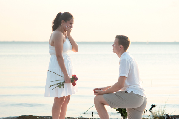 Young man proposing to his girlfriend at the beach.