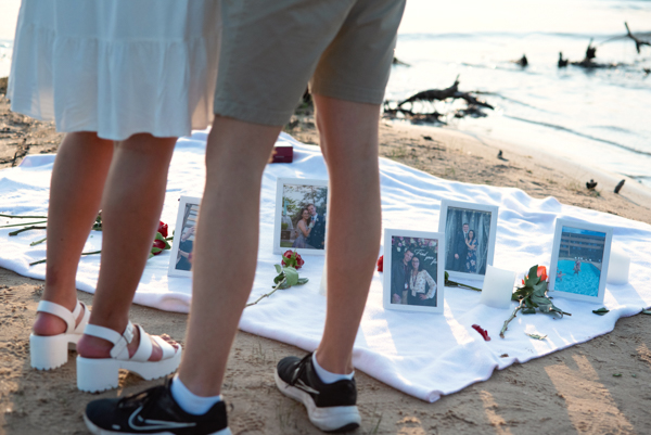 Couple standing over a blanket filled with framed pictures of their courtship.