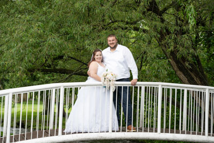 Bride and Groom standing on white bridge at Iron's Park in West Branch, mIafter their micro-wedding,