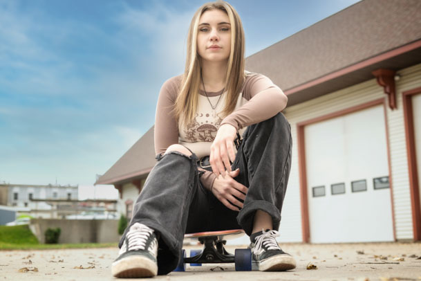 High School Senior sitting on skateboard