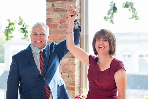 Wedding couple, just married-hands in the air in celebration.
